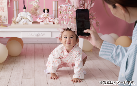 赤ちゃんと親王飾りスタイルの雛人形（ひな人形）をスマホで撮影しているところ